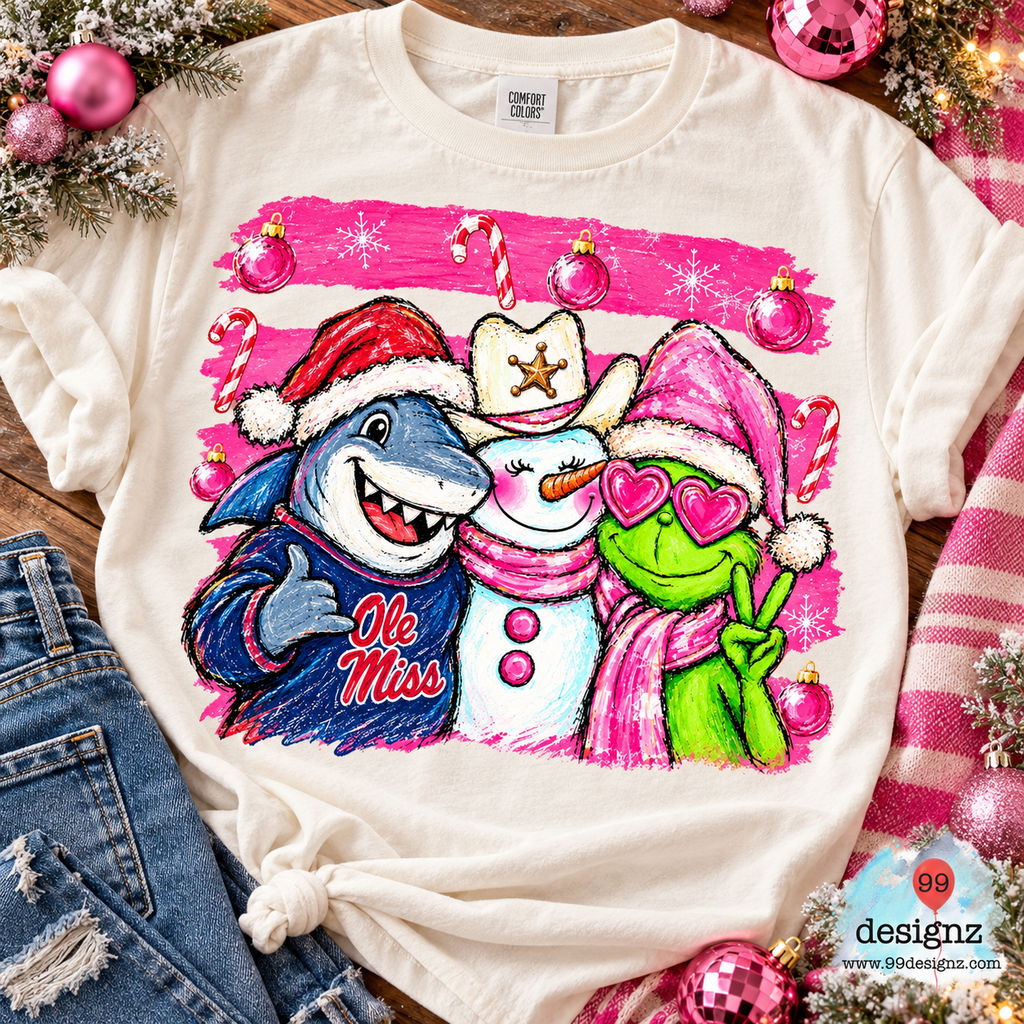 Cream T-shirt flat-lay mockup showing Ole Miss Christmas PNG artwork with a shark, cowboy snowman, and green holiday character.